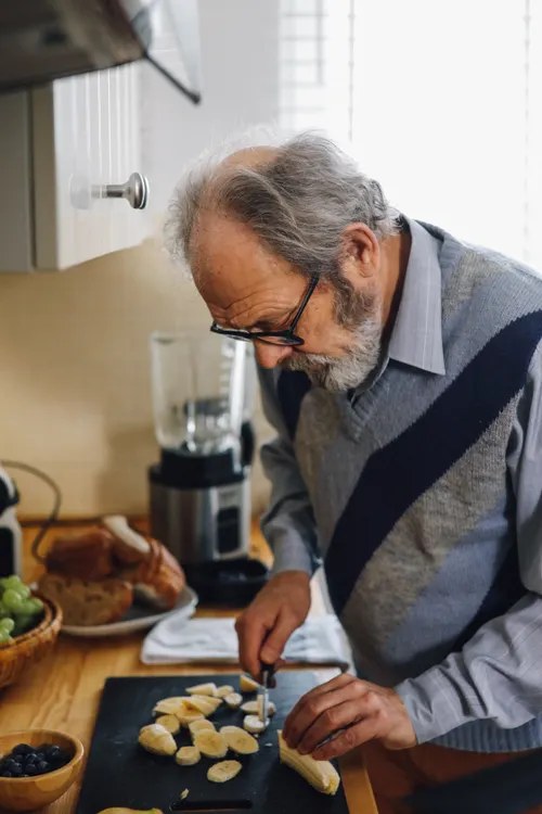 A caregiver and senior preparing fresh food together